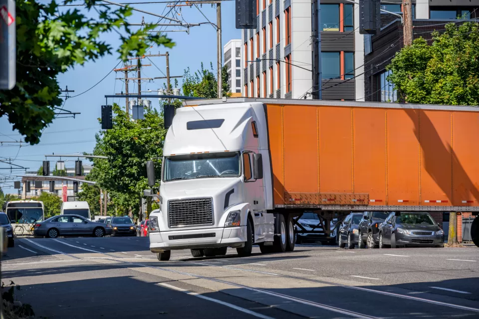 Orange big rig truck turning on a city street